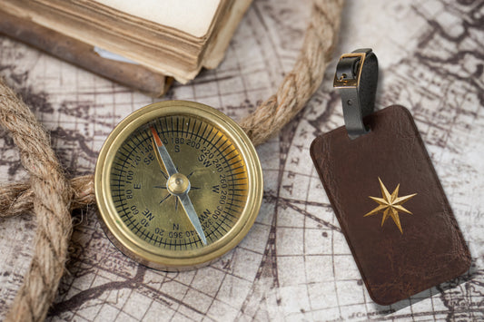 Kofferanhänger mit goldenem Polarstern auf dunkelbrauner Lederoptik, arrangiert mit Kompass, Seil und historischer Karte als Symbol für Orientierung und Entdeckergeist.
