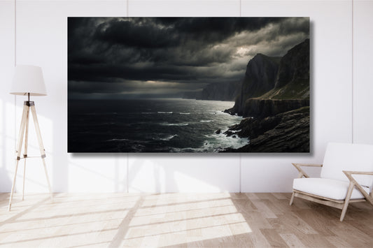 Poster einer dunklen Küstenlandschaft an einer weißen Wand in einem hellen Wohnzimmer mit Holzfußboden und modernem Sessel.