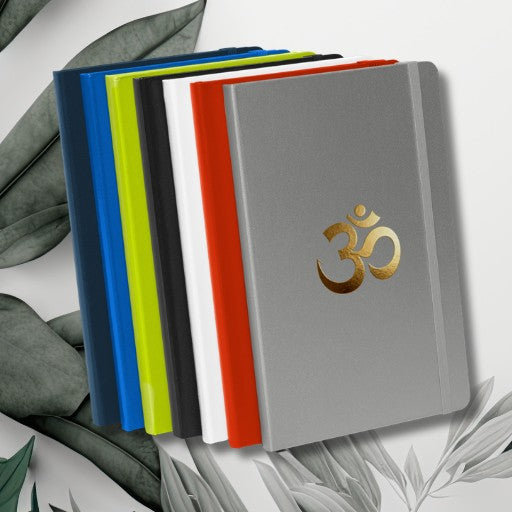 Hardcover Notizbuch mit goldenem Om-Symbol, erhältlich in verschiedenen Einbandfarben.