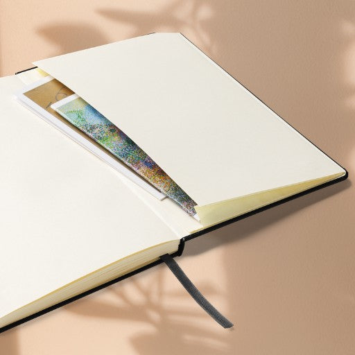 Hardcover Notizbuch mit geöffneten cremefarbenen Seiten und integrierter Innentasche für lose Notizen oder Visitenkarten.