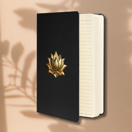 Hardcover Notizbuch mit goldener Lotusblüte auf schwarzem Einband in geöffneter Vorderansicht mit cremefarbenen linierten Seiten.