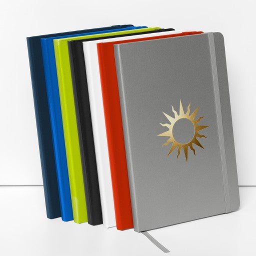 Spiralnotizbuch mit goldenem Sonnensymbol, erhältlich in verschiedenen Einbandfarben.