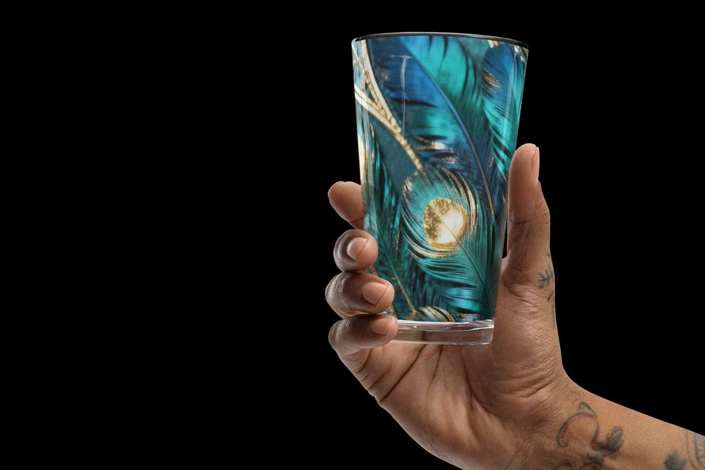 Glas mit türkis-goldenem Federmotiv in einer Hand vor schwarzem Hintergrund