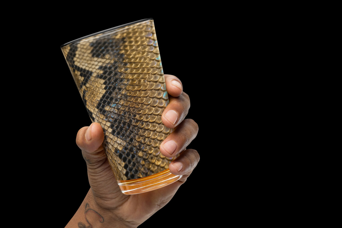 Gold-schwarzes Strukturglas mit glänzender Reptilienoptik in der linken Hand gehalten