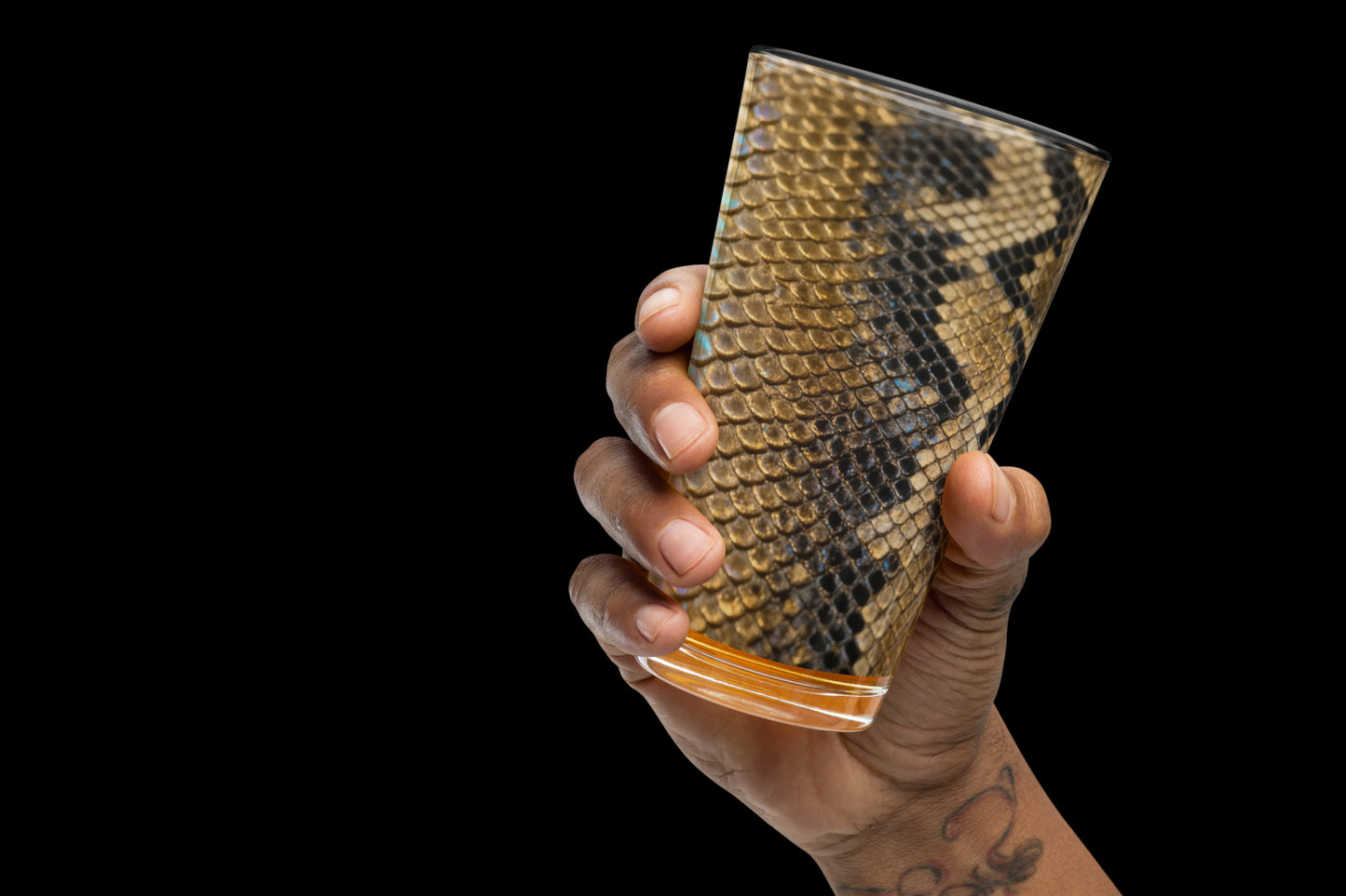 Gold-schwarzes Strukturglas mit glänzender Reptilienoptik in der rechten Hand gehalten