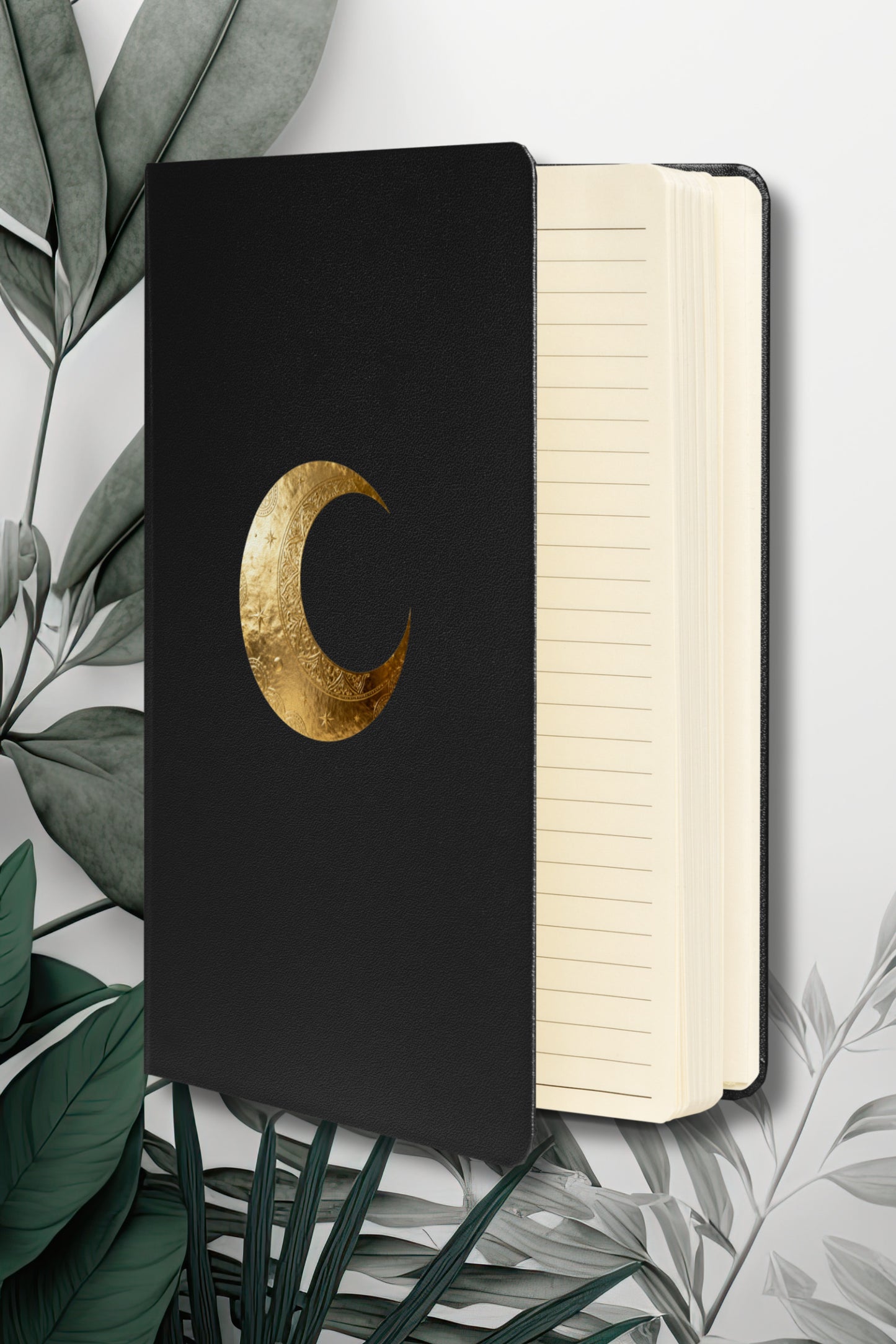 Hardcover Notizbuch mit goldenem Mondsymbol auf schwarzem Einband, geöffnet mit linierten cremefarbenen Seiten.