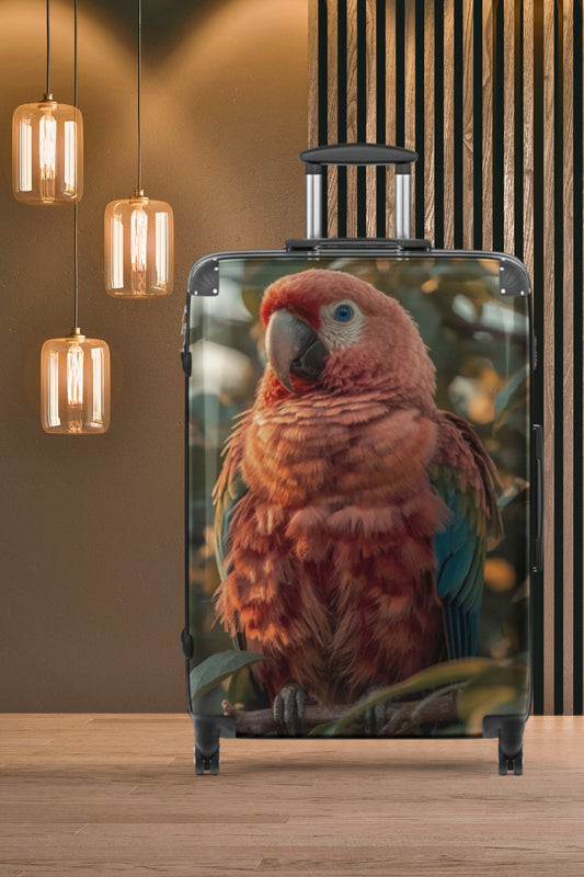 Hartschalenkoffer mit farbenprächtigem Ara-Motiv vor einer stilvollen Innenraumkulisse mit Pendelleuchten und warmer Lichtstimmung. Die detailreiche Darstellung des exotischen Vogels macht den Koffer zu einem besonderen Blickfang auf Reisen.