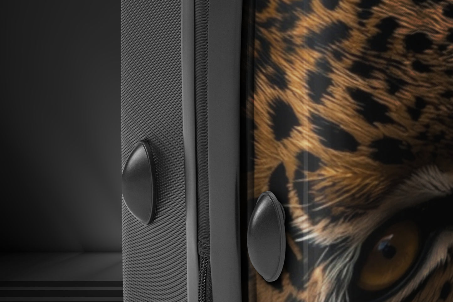 Detailaufnahme eines Hartschalenkoffers mit Leopardenmotiv, sichtbar sind das intensive Auge des Leoparden, die bedruckte Vorderseite und die strukturierte Seitenfläche des Koffers.