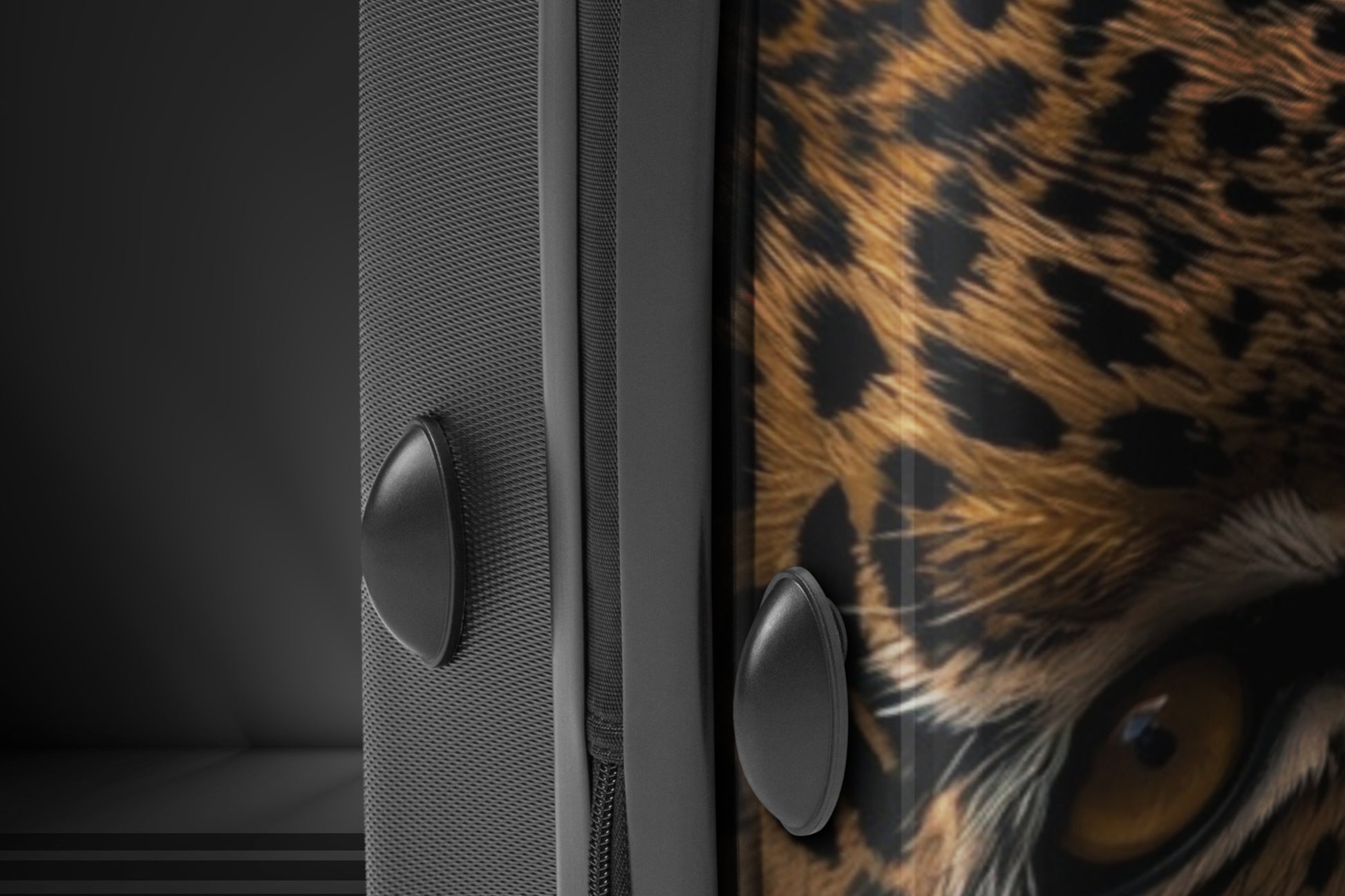 Detailaufnahme eines Hartschalenkoffers mit Leopardenmotiv, sichtbar sind das intensive Auge des Leoparden, die bedruckte Vorderseite und die strukturierte Seitenfläche des Koffers.