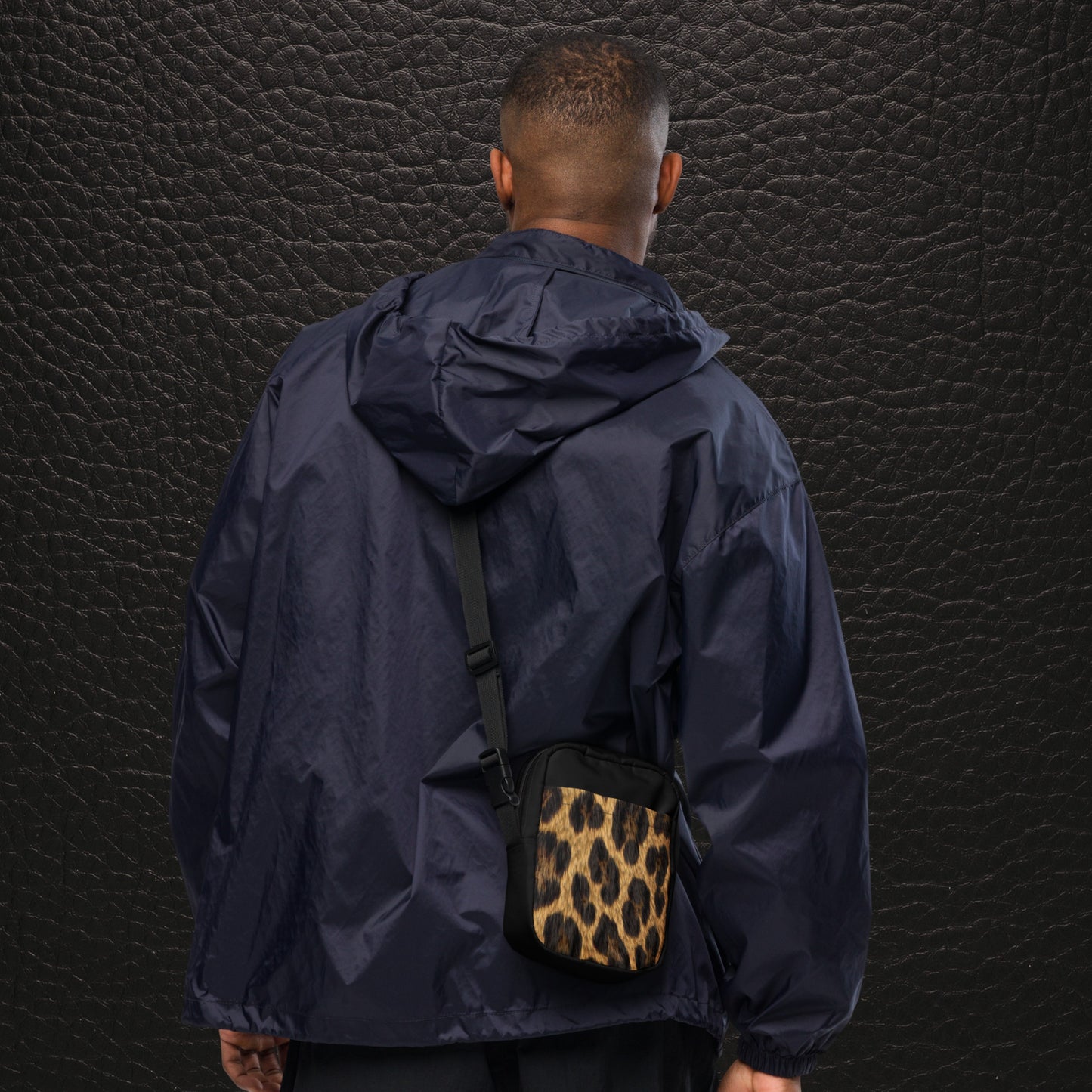 Crossbody Bag mit Jaguarfell-Print an der Rückseite, getragen von einem Mann hinten, verstellbarer Schultergurt, schwarze Seiten