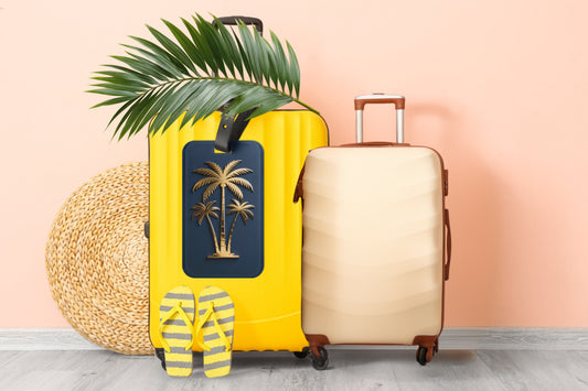 Kofferanhänger mit goldener Palmensilhouette auf tiefblauem Hintergrund präsentiert zwischen Reisekoffern, Palmenblatt, Strohhut und Sandalen in sommerlicher Urlaubsatmosphäre.