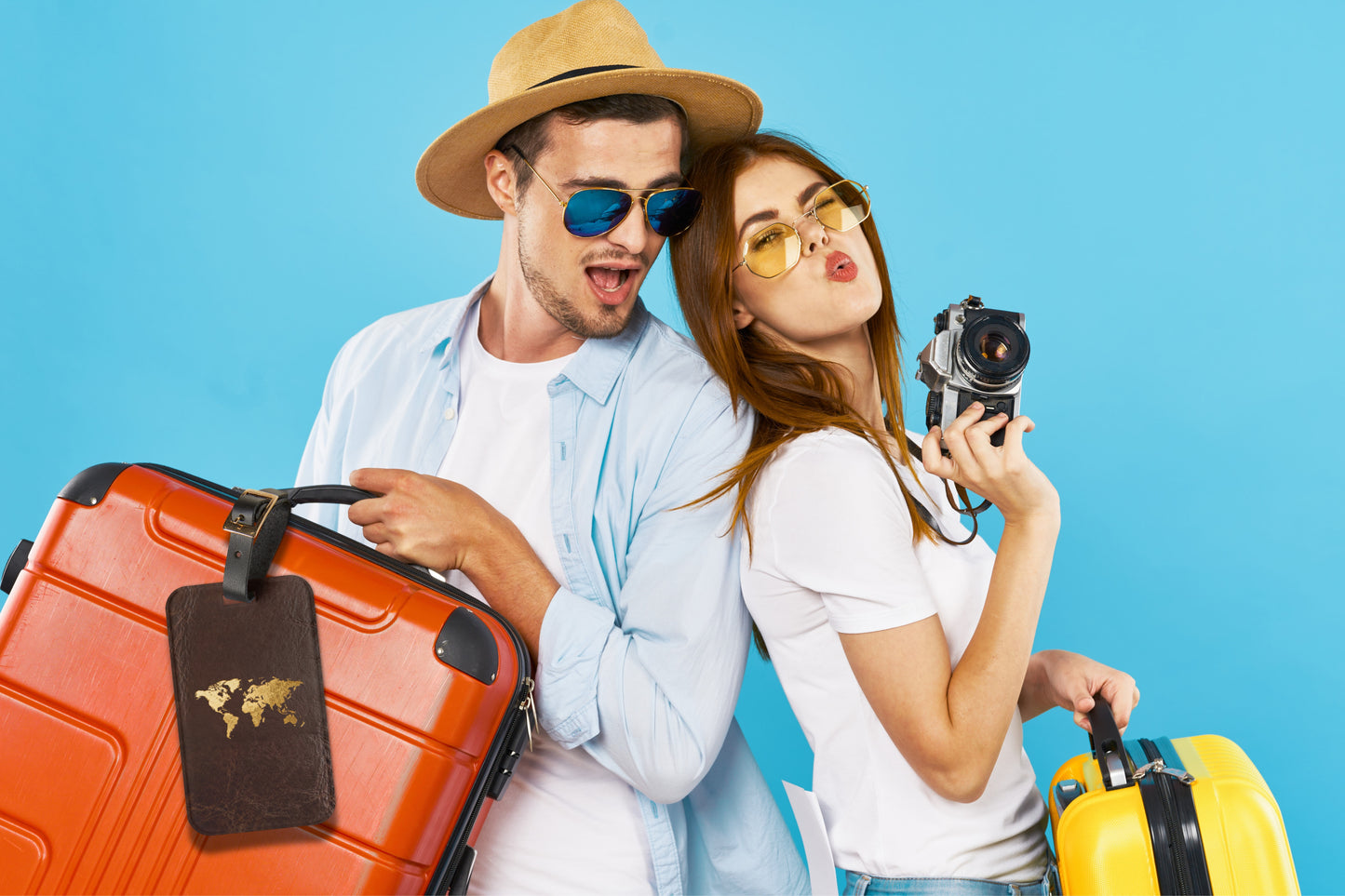 Kofferanhänger mit goldener Weltkarte auf dunkelbrauner Lederoptik, befestigt an einem Reisekoffer und präsentiert in einer sommerlichen Reiseszene mit Urlaubern und Gepäck.