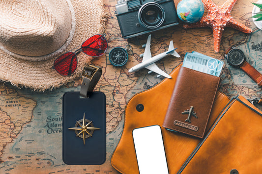 Kofferanhänger mit goldener Windrose auf einer Reisekarte umgeben von Reiseaccessoires wie Kamera, Kompass, Reisepass und Sonnenhut