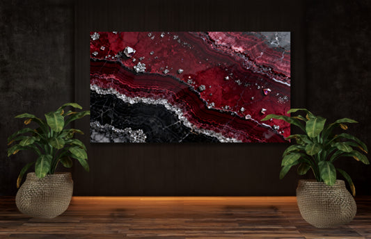 Leinwand mit granatroter Mineralstruktur, schwarzen Marmorschichten und silbernen Kristallakzenten an dunkler Wand zwischen zwei Zimmerpflanzen.