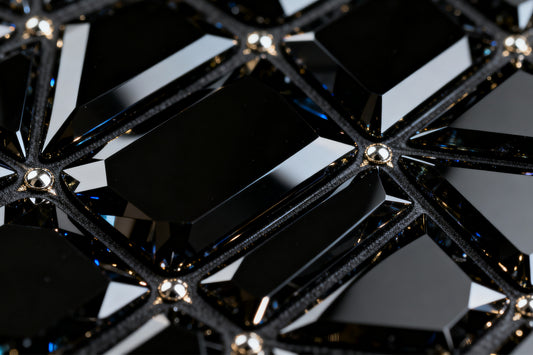 Detailaufnahme der facettierten Kristallstruktur eines schwarzen Obsidian Glases mit glänzenden Reflexen