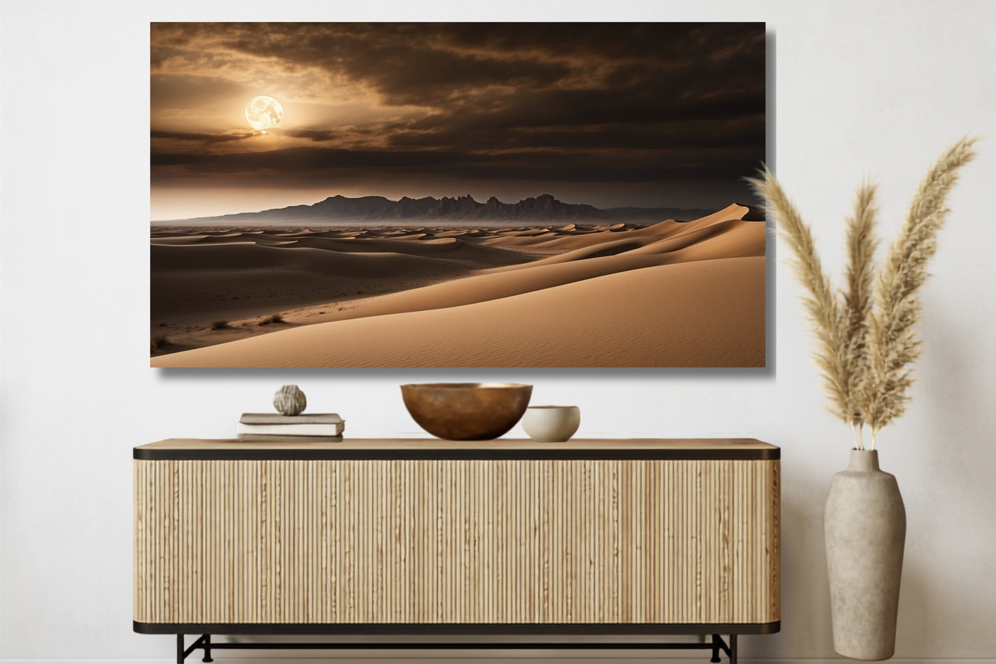 Poster einer Wüstenlandschaft im Vollmondlicht über einem Sideboard an einer weißen Wand mit stilvoller Dekoration und Pampasgras.