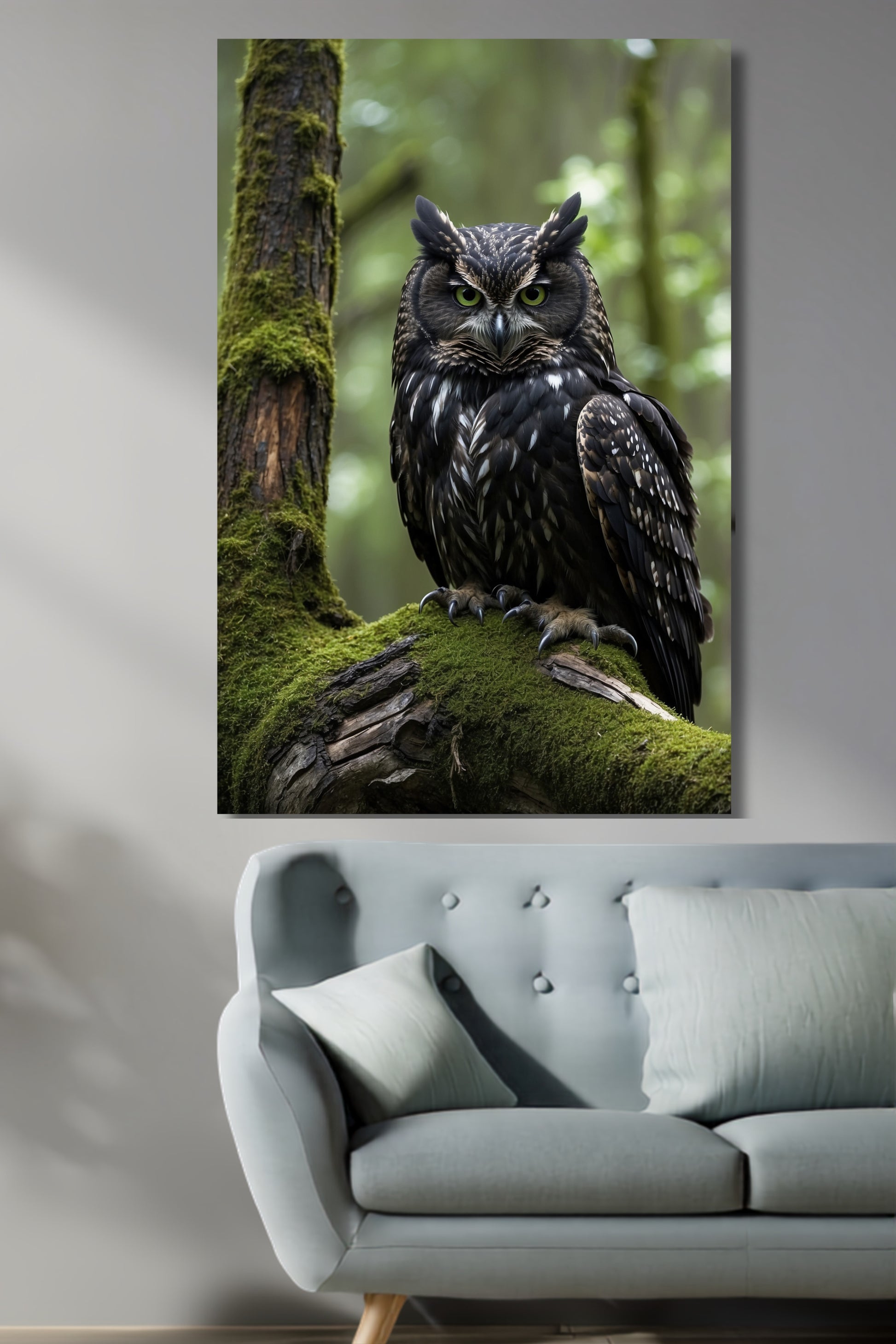 Poster Eule im moosigen Wald als Wandkunst über einem hellgrauen Sofa vor heller Wand mit seitlich einfallendem Tageslicht.