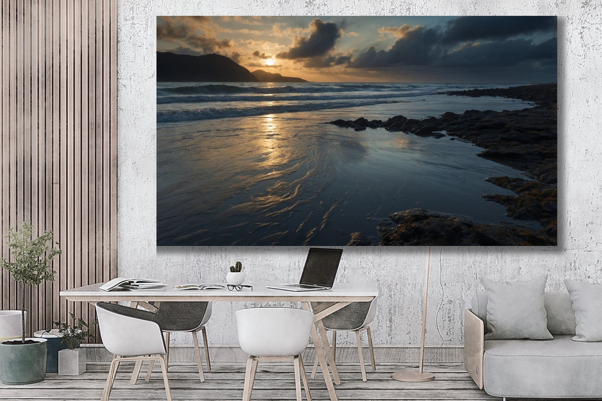 Poster einer Meereslandschaft in der Dämmerung über einem Arbeitstisch mit laptop in einem modernen Wohnraum mit Holzlamellenwand, heller Strukturwand und Sofa