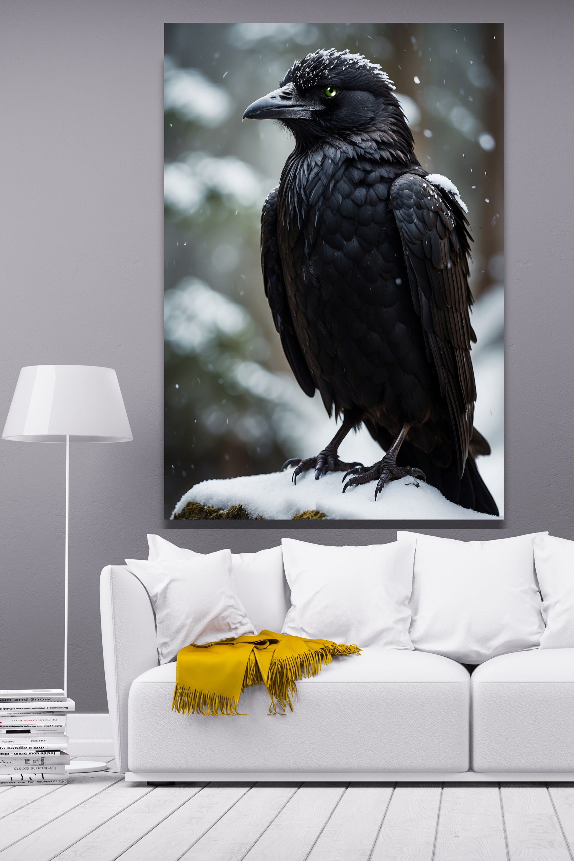 Poster Rabe mit grünem Auge im Winter als Wandkunst über einem weißen Sofa mit gelber Decke und Stehlampe vor einer hellgrauen Wand.