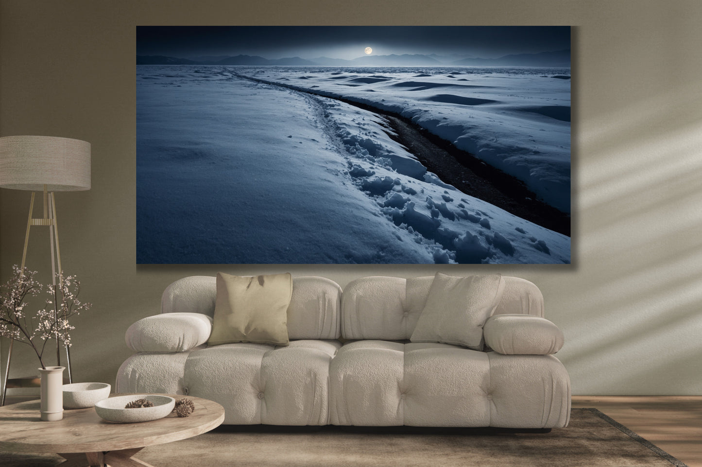 Poster einer Schneelandschaft im sanften Mondlicht über einem cremefarbenen Sofa in einem modernen Wohnzimmer mit Stehlampe und rundem Couchtisch.