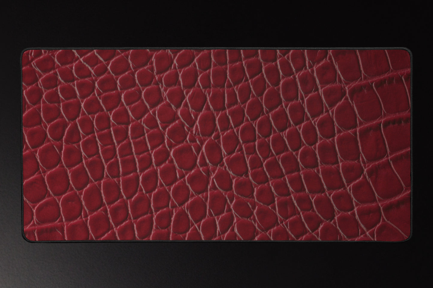 Rote Schreibtischunterlage mit luxuriöser Kroko-Lederstruktur und schwarzem Rand auf dunklem Hintergrund