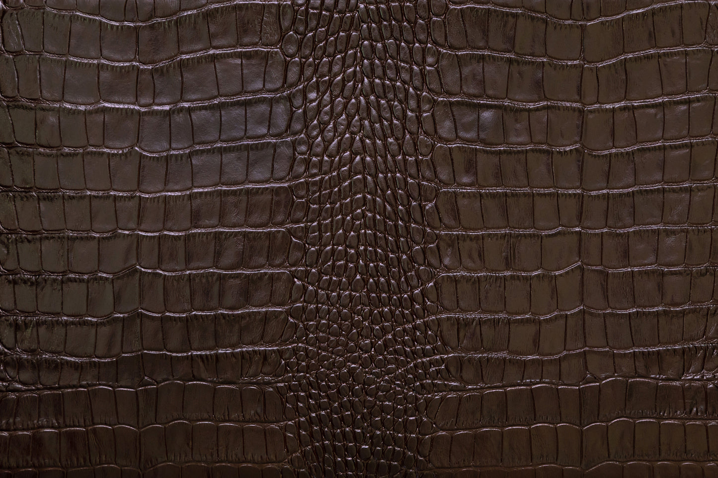 Detailaufnahme der strukturierten dunkelbraunen Krokolederoptik mit präziser Oberflächenstruktur und Lichtreflexen.