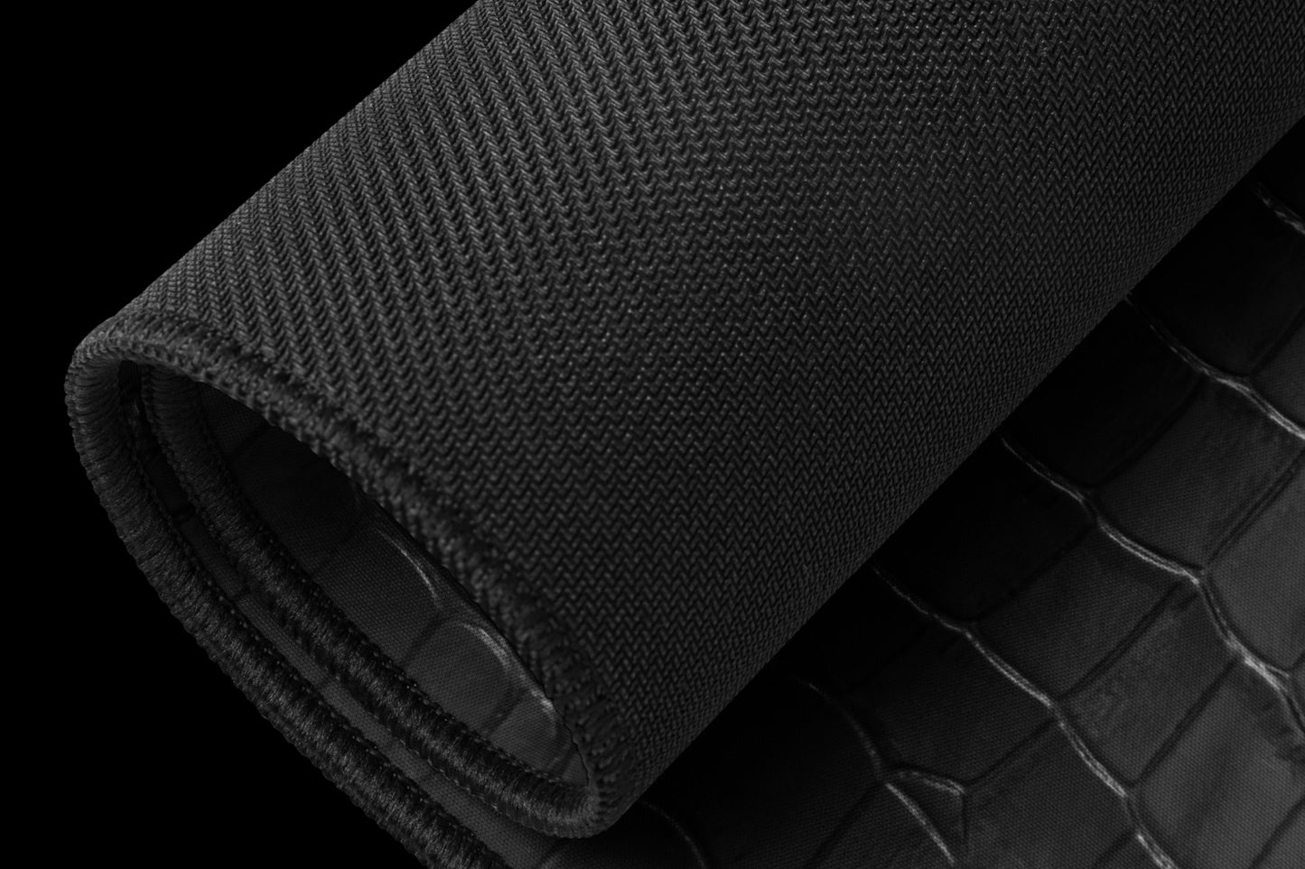 Schwarze gerollte Desk Mat mit schwarzer Unterseite und strukturierter Krokolederoberfläche.