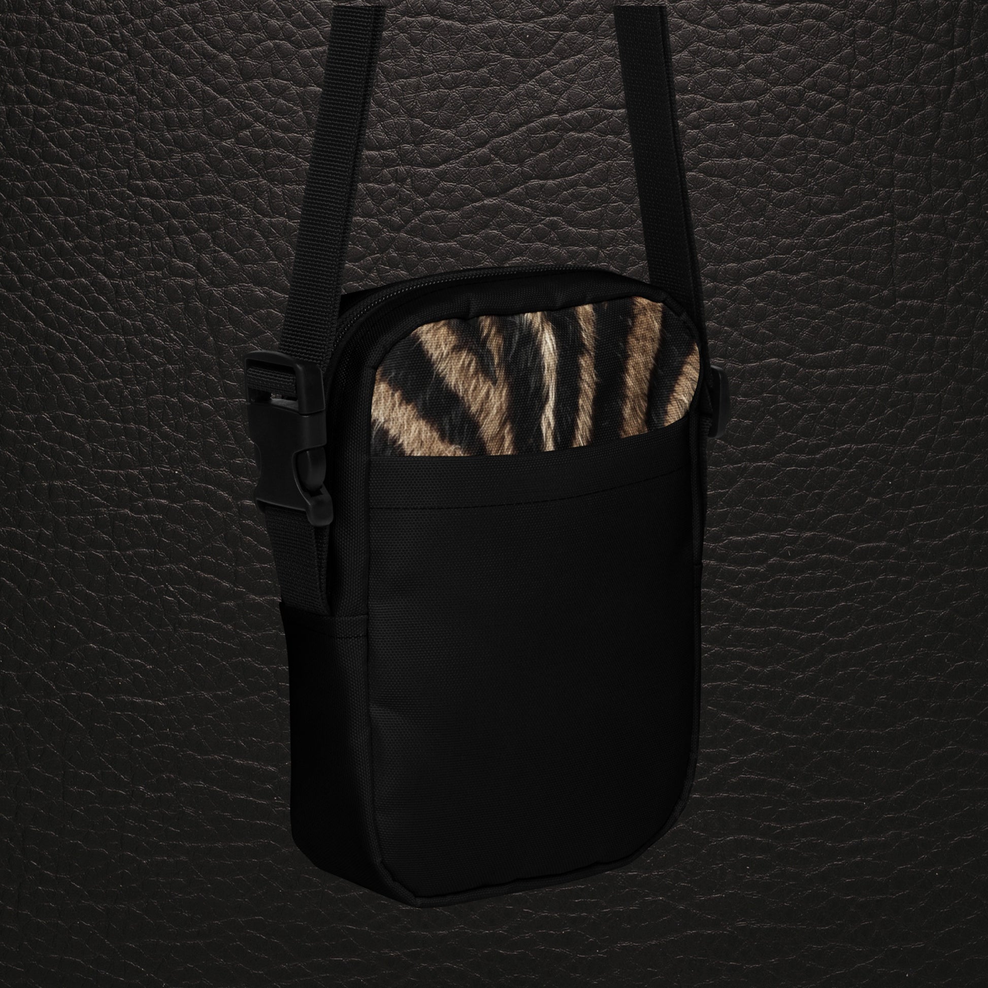 Schrägansicht der Vorderseite der kompakten Zebra Muster Tasche mit natürlichem Fellprint, schwarzer Außentasche und schwarzem Trageriemen