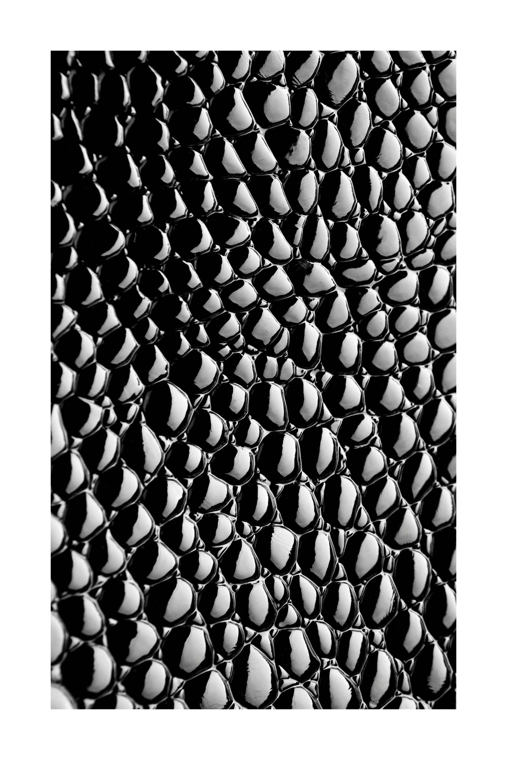 Freigestelltes schwarzes Strukturglas mit glänzender monochromer Reptilienoptik und luxuriöser Tiefenwirkung