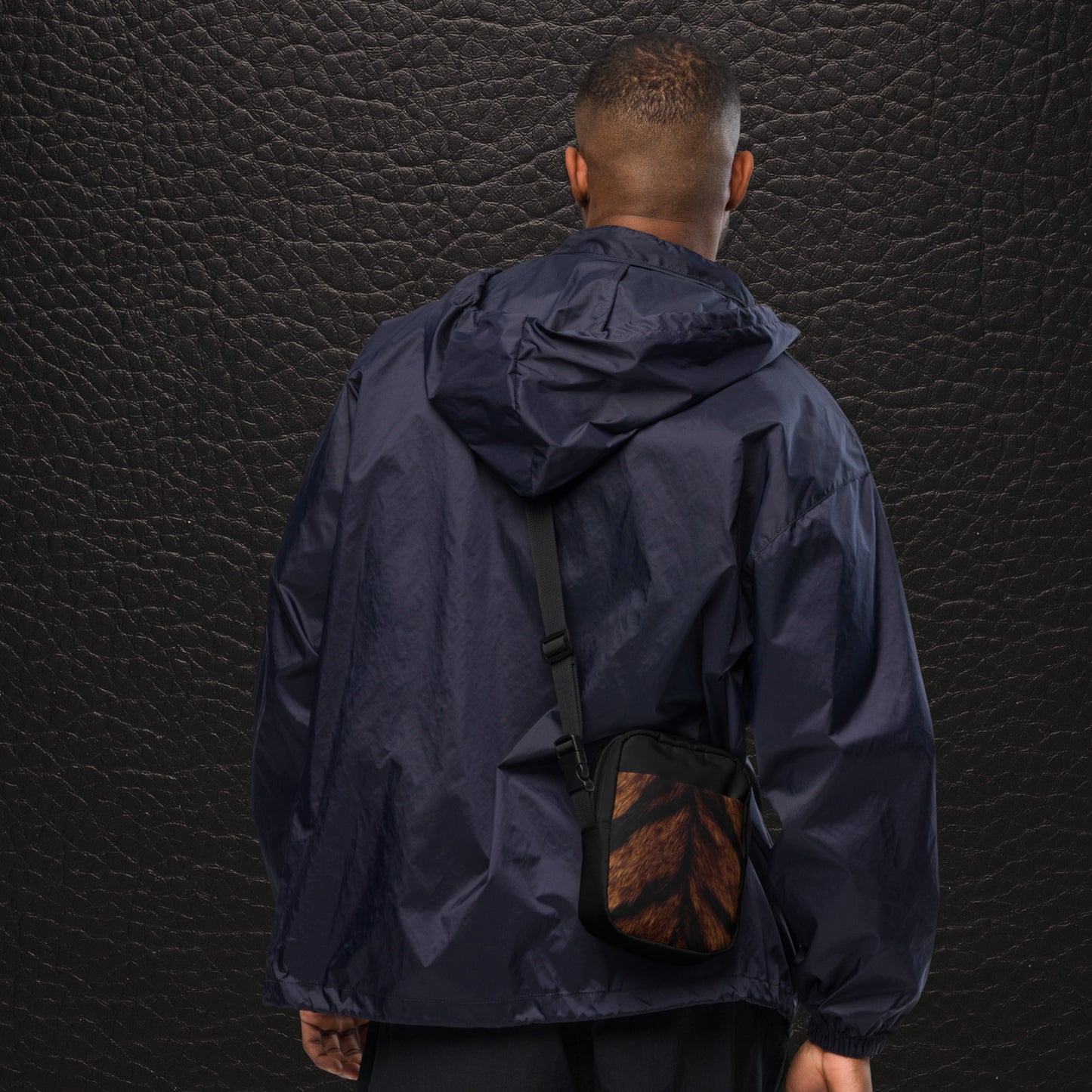 Tigerfell Crossbody Bag getragen von einem Mann von hinten mit dunklem Tragesystem und kompakter Form